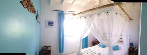 a bedroom with a white canopy bed with a window at Horizon Karukera in Sainte-Rose