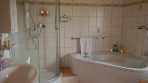y baño con ducha, bañera y lavamanos. en Ferienhaus Rosemarie, en Breungeshain