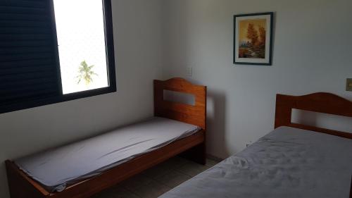 a small bedroom with two beds and a window at Caraguá Martins de Sá in Caraguatatuba