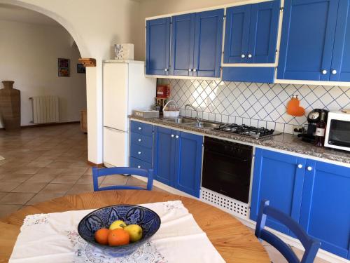 サン・パンタレオにあるLa casa bluのキッチン(青いキャビネット付)、フルーツボウル1杯(テーブル上)