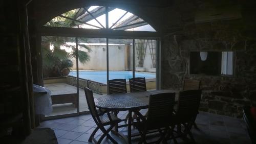 une salle à manger avec une table et des chaises ainsi qu'une piscine dans l'établissement La perle cachée, à Fontcouverte