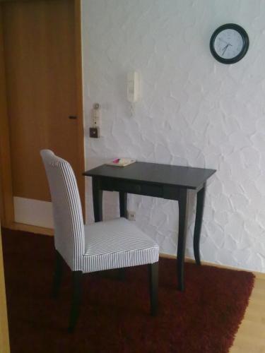 a desk with a chair and a clock on a wall at Pension Eltmann in Eltmann