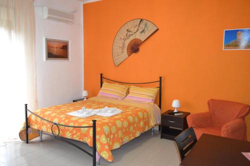 ein Schlafzimmer mit einem Bett mit einer orangefarbenen Wand in der Unterkunft Casa Vacanze Laura in Isola delle Femmine