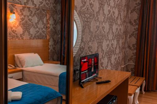 a hotel room with a bed and a television on a desk at Pera City Hotel in Ankara