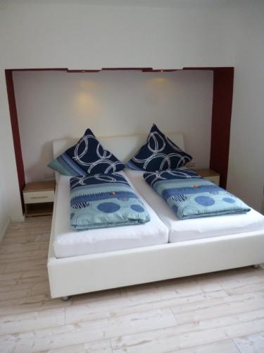 a bed with blue and white pillows on it at Gästehaus Laßbruch in Extertal