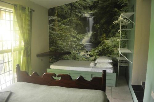 a bedroom with a waterfall mural on the wall at Leatherback Lodge Eco B&B in Salybia