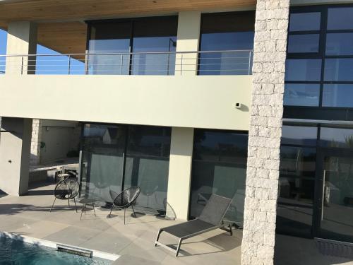 a patio with chairs and a pool in a building at Villa d'exception, piscine, vue mer, plage à 100M in Ajaccio