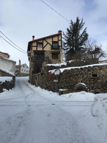 a snow covered street with a building in the background at Artesano II in Navarredonda de Gredos