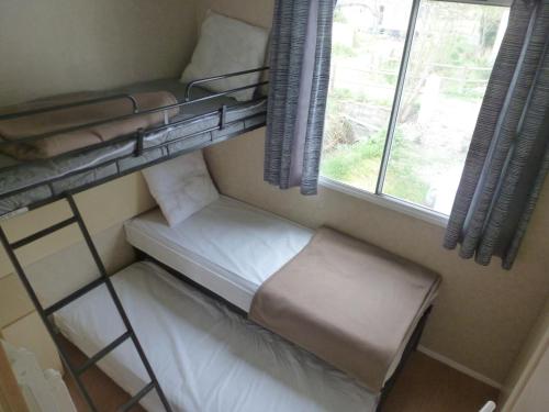 シジャンにあるMobil-Home a Sigeanの二段ベッド2台、窓が備わる小さな客室です。
