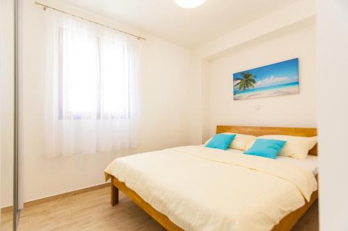 a white bedroom with a bed with blue pillows at Deluxe Villa Nina in Novi Vinodolski