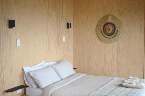 a bedroom with a bed with a hat on the wall at The Huts in Ahipara
