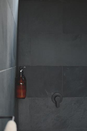 a bathroom with a soap dispenser on a wall at The Huts in Ahipara