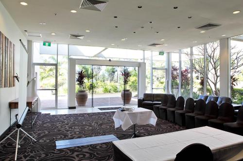 a hotel room with tables and chairs in it at Absolute Beachfront Opal Cove Resort in Coffs Harbour
