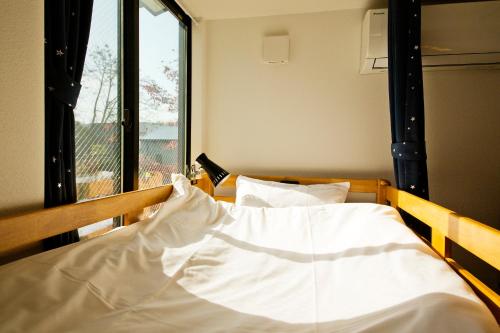 a bedroom with a bed with white sheets and a window at add-Hostel Uji Cha-gan-ju-tei in Uji