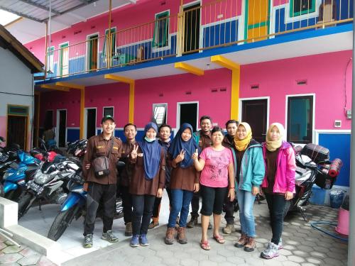 a group of people standing in front of a pink building at Homestay Lidiya in Banyuwangi