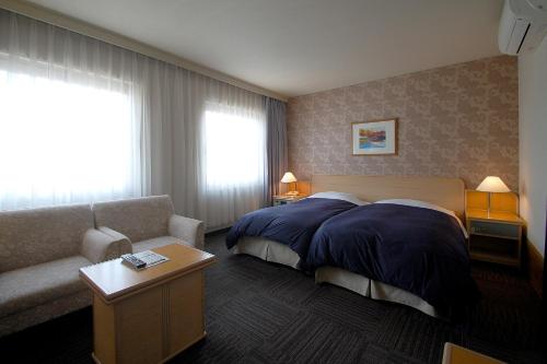 岡山市にあるホテルエクセル岡山のベッドとソファ付きのホテルルーム