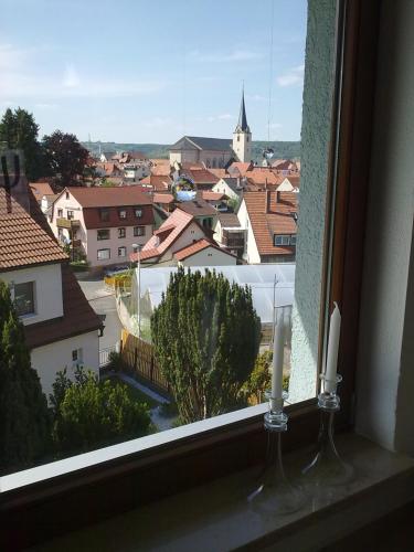 a view of a city from a window with two candles at Pension Eltmann in Eltmann