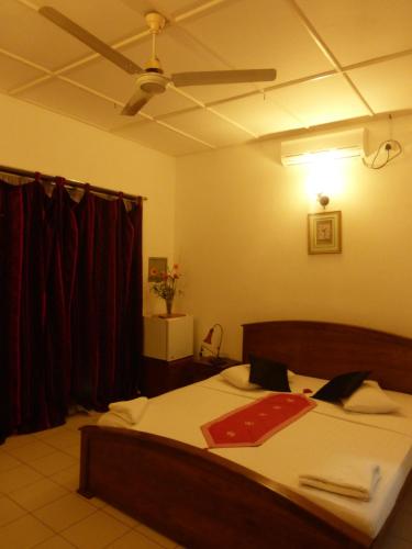 a bedroom with a bed with a ceiling fan at Snowdrop in Negombo