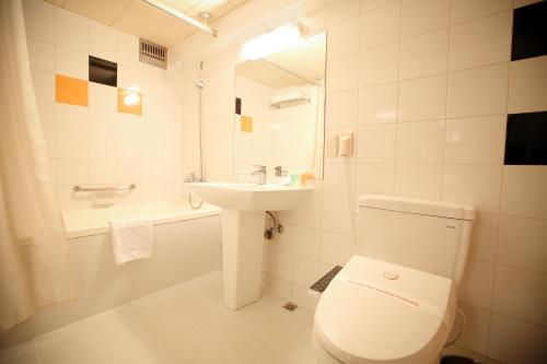 a white bathroom with a toilet and a sink at Savoy Hotel Myeongdong in Seoul