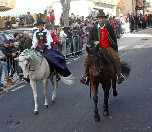 two men riding horses in a parade with a crowd at Aria d' Prè in Badia