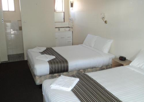 a hotel room with two beds and a mirror at Coffs Harbour Pacific Palms Motel in Coffs Harbour