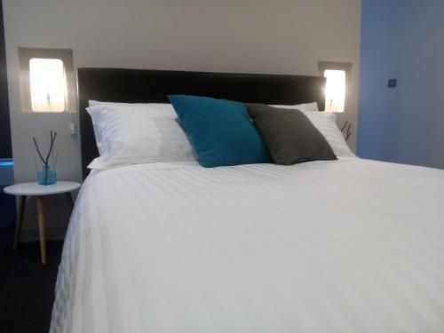 a large white bed with two blue pillows on it at East 34 in Ballarat