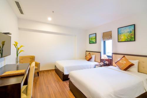a hotel room with two beds and a desk at Dana Marina Boutique Hotel in Da Nang
