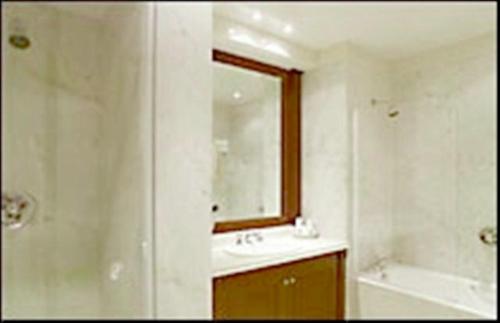 
a bathroom with a tub, sink and mirror at Hotel Amsterdam in Mar del Plata

