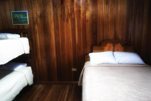 two beds in a room with wood paneling at Hotel Caribbean View in Bastimentos
