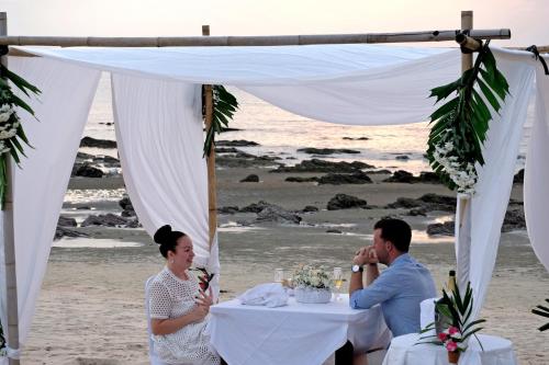 a man and a woman sitting at a table on the beach at Andaman Lanta Resort - SHA Extra Plus in Ko Lanta