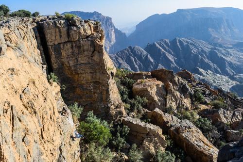 a person standing on a cliff in the mountains at Anantara Al Jabal Al Akhdar Resort in Al ‘Aqar