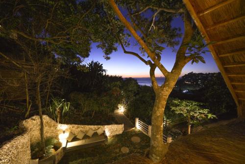 a bench sitting under a tree with a view of the ocean at Diniview Villa Resort in Boracay