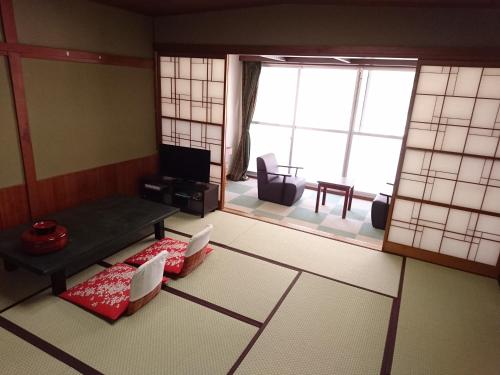 a living room with a table and chairs and windows at Ichiryukaku Honkan in Nikko