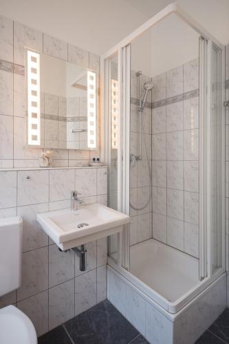 a white bathroom with a shower and a sink at Hotel Brandenburger Hof in Cologne