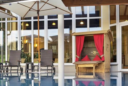 a patio with chairs and an umbrella next to a pool at Wellness- und Vitalhotel Böhmhof in Bodenmais