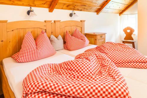 a bed with red and white checkered pillows on it at Wohlfühlbauernhof Bambichlhof in Fuschl am See