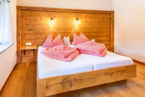 a bed with red and white pillows on it at Wohlfühlbauernhof Bambichlhof in Fuschl am See