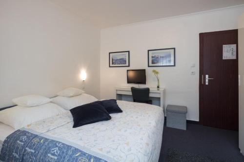 a bedroom with a bed and a desk with a television at Hotel Brandenburger Hof in Cologne