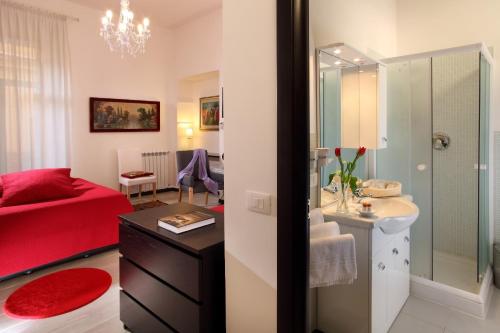 bagno con letto rosso, lavandino e specchio di Roma Central Guest House a Roma