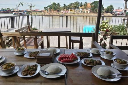 a wooden table with plates of food on it at ST 63 Home Stay & Tour Kampong Khleang in Kâmpóng Khleăng