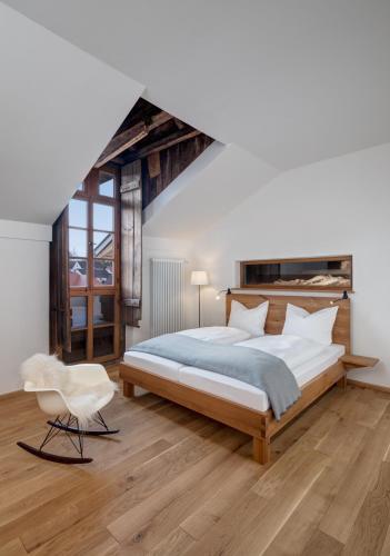 SinzingにあるHotel Röhrlの大きなベッドと椅子のある寝室