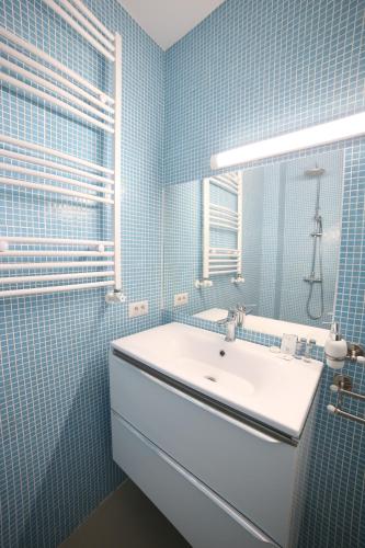 a blue tiled bathroom with a sink and a mirror at Fresh Accommodation in Rădăuţi