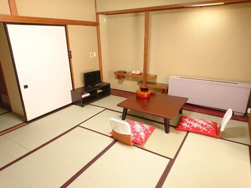 a room with a table and two chairs and a table and a tv at Ichiryukaku Honkan in Nikko