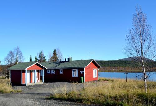 a red and white house next to a body of water at Talo Ylläs in Äkäslompolo