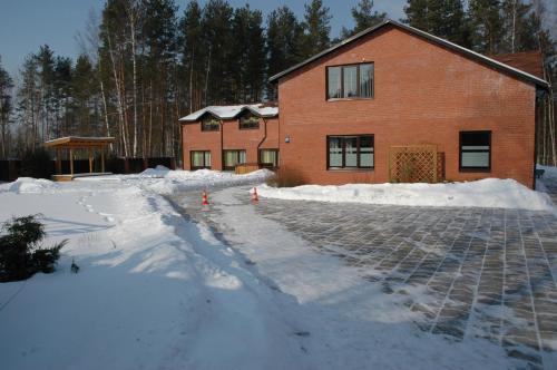 a house in the snow with two orange cones in front at Strenči Guesthouse in Strenči
