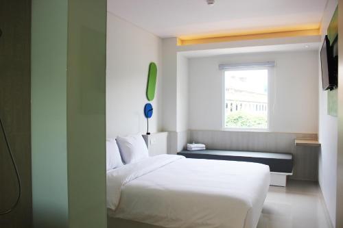 um quarto com uma cama branca e uma janela em POP! Hotel Pemuda Semarang em Semarang