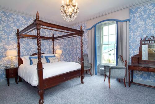 a bedroom with a canopy bed and blue wallpaper at Rockhill House in Letterkenny