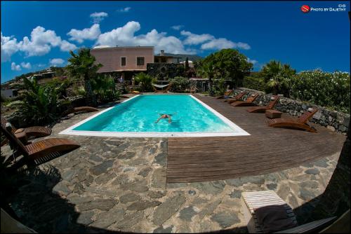 une personne nage dans une piscine avec des chaises dans l'établissement La Kuddia, à Pantelleria