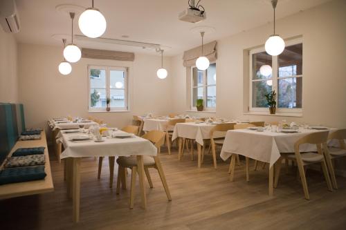 a restaurant with white tables and chairs and windows at Ditlin in Pápa