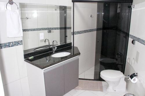 a bathroom with a sink and a shower and a toilet at Hotel Bellagio in Campo Grande